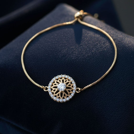 Abidii Everly Bracelet – slim gold-tone bracelet with a round center motif and pavé halo, displayed on dark fabric, showing its radiant, detailed design.