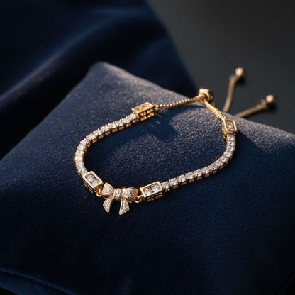 Abidii Loyalty Knot Bracelet – rose-gold-tone bracelet with pavé bow centre and slider closure, displayed on dark fabric in soft light.