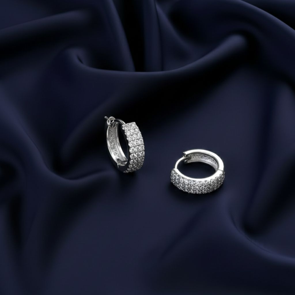 Abidii Luna Hoops – silver tone pavé hoop earrings displayed on a soft fabric surface, highlighting their minimal shape and cool shine.