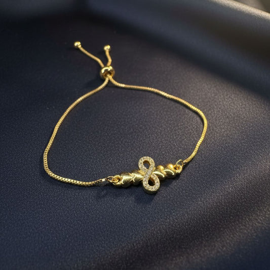 Abidii Promise Link Bracelet – slim gold-tone bracelet with pavé infinity symbol and linked accents, displayed on dark fabric, showing its delicate, adjustable design.