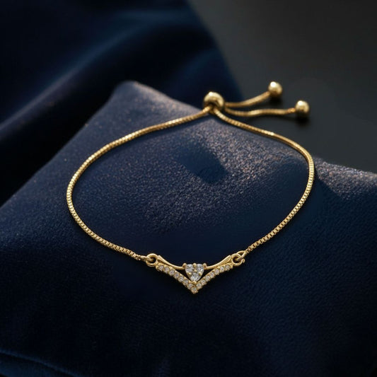 Abidii Tiara Bracelet – slim gold-tone bracelet with a V-shaped pavé centre and three stones in a triangle, displayed on dark fabric, showing its delicate crown-like design.