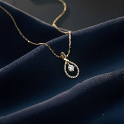 Abidii Zenith Set – teardrop halo pendant necklace with matching drop earrings displayed on dark, folded fabric, showing their luminous stones and elegant, elongated design.
