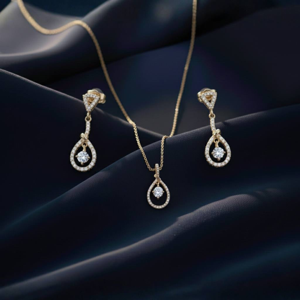 Abidii Zenith Set – teardrop halo pendant necklace with matching drop earrings displayed on dark, folded fabric, showing their luminous stones and elegant, elongated design.